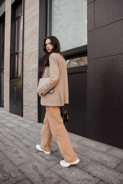 Tall modern girl designer with a laptop in her hands goes to work in the office