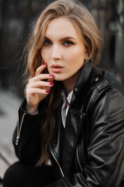 Kentin arka planında siyah deri ceketli, gülümseyen güzel sarışın bir kadının portresini yakından çek.