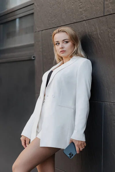 Blond Stylish Woman Oversized White Jacket Using Phone Modern City —  Fotos de Stock