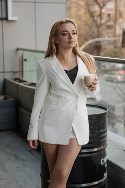 Светловолосая Стильная Женщина Огромной Белой Куртке Пьющая Ароматный Кофе Отдыхающая — стоковое фото
