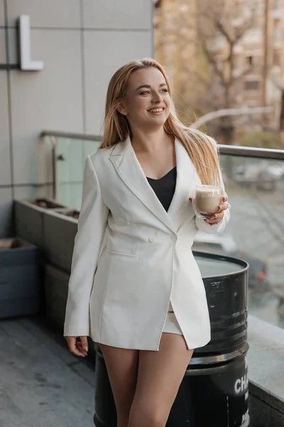 Blondynka Stylowa Kobieta Ponadwymiarowej Białej Kurtce Pijąca Aromatyczną Kawę Relaksująca — Zdjęcie stockowe