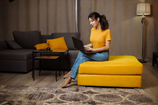 Happy indian or arabian young freelance woman on sofa and using laptop. Remote working
