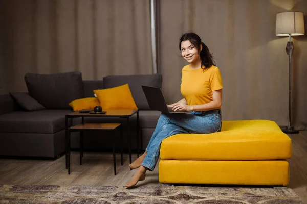 Happy indian or arabian young freelance woman on sofa and using laptop. Remote working