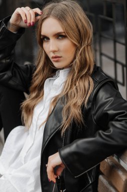 Kentin arka planında siyah deri ceketli, gülümseyen güzel sarışın bir kadının portresini yakından çek.