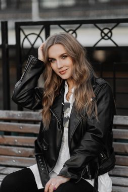 Kentin arka planında siyah deri ceketli, gülümseyen güzel sarışın bir kadının portresini yakından çek.