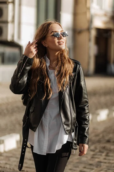 Modisches Blondes Frauenmodel Mit Schwarzer Lederjacke Und Stilvoller Sonnenbrille Spaziert — Stockfoto