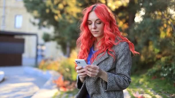 若い赤毛のビジネス自信のある女性 市の日没の背景のスマートフォン屋外を使用して — ストック動画