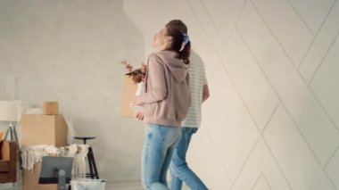 Yeni Evde Yürüyen Genç Bir Çift Son Şeyleri Getiriyorlar. Çift yeni evi tartışıyor. Mutlu çift kanepeye oturup dinleniyor. Kutu Taşıyan Adam ve Kız Çiçekleri.