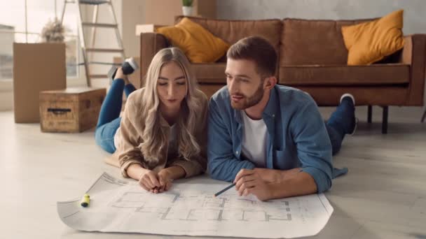 Couple Discussing Flat Plan Lying Floor Couple Moving New Home — Stock video