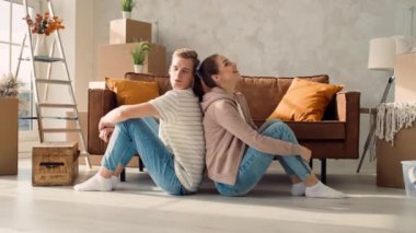 Couple Sitting Back to Back in a New Home. Couple Moving to a new House.