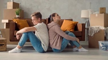 Couple Sitting Back to Back in a New Home. Couple Moving to a new House.