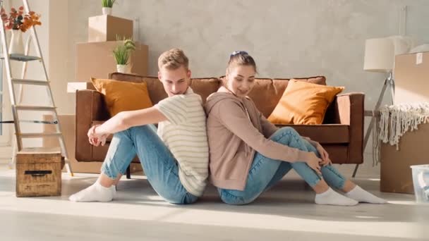 夫妻背靠背地坐在一个新家 夫妻搬入新居 — 图库视频影像