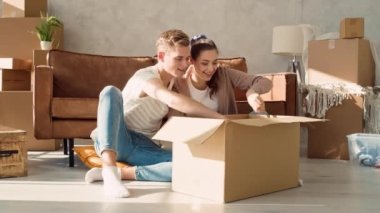 Couple Unpacking Goods from Box. Couple Moving to New Home.