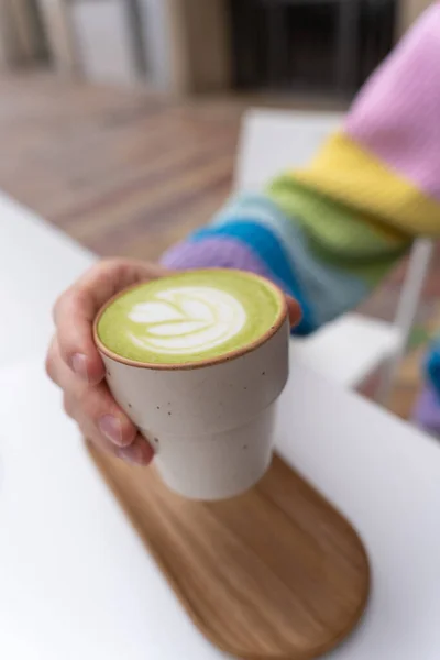 Manos Hombre Sosteniendo Macha Latte Cup Con Placa Madera Caffe Imagen de stock