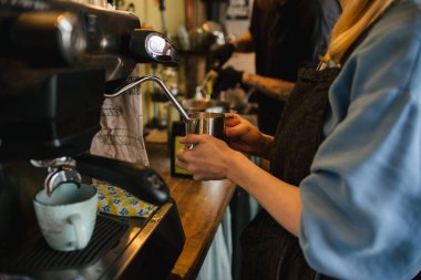 Kız kahve makinesinde kahve yapıyor. Latte için süt fısıltısı. Sütlü kahve.
