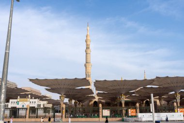 Medine, Suudi Arabistan - 18 Aralık 2024: Medine 'deki Büyük Kral Abdullah Camii' nin dev şemsiyeleri altındaki hacılar, Suudi Arabistan 'ın ikinci en kutsal İslam mekanı.