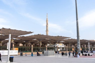 Medine, Suudi Arabistan - 18 Aralık 2024: Medine 'deki Büyük Kral Abdullah Camii' nin dev şemsiyeleri altındaki hacılar, Suudi Arabistan 'ın ikinci en kutsal İslam mekanı.