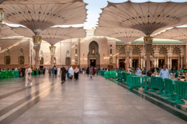 Medine, Suudi Arabistan - 18 Aralık 2024: Medine 'deki Büyük Kral Abdullah Camii' nin dev şemsiyeleri altındaki hacılar, Suudi Arabistan 'ın ikinci en kutsal İslam mekanı.