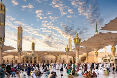 Medine, Suudi Arabistan - 18 Aralık 2024: Medine 'deki Büyük Kral Abdullah Camii' nin dev şemsiyeleri altındaki hacılar, Suudi Arabistan 'ın ikinci en kutsal İslam mekanı.
