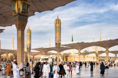Medine, Suudi Arabistan - 18 Aralık 2024: Medine 'deki Büyük Kral Abdullah Camii' nin dev şemsiyeleri altındaki hacılar, Suudi Arabistan 'ın ikinci en kutsal İslam mekanı.
