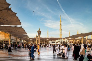 Medine, Suudi Arabistan - 18 Aralık 2024: Medine 'deki Büyük Kral Abdullah Camii' nin dev şemsiyeleri altındaki hacılar, Suudi Arabistan 'ın ikinci en kutsal İslam mekanı.