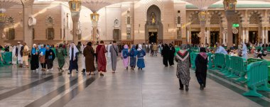 Medine, Suudi Arabistan - 18 Aralık 2024: Medine 'deki Büyük Kral Abdullah Camii' nin dev şemsiyeleri altındaki hacılar, Suudi Arabistan 'ın ikinci en kutsal İslam mekanı.