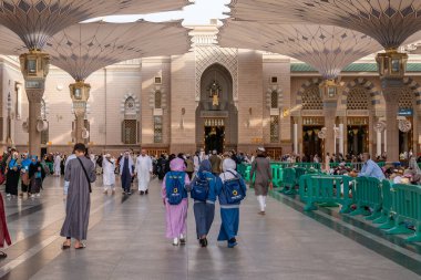 Medine, Suudi Arabistan - 18 Aralık 2024: Medine 'deki Büyük Kral Abdullah Camii' nin dev şemsiyeleri altındaki hacılar, Suudi Arabistan 'ın ikinci en kutsal İslam mekanı.