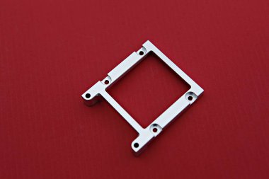 Kırmızı bir yüzey üzerinde bir kare metal nesne