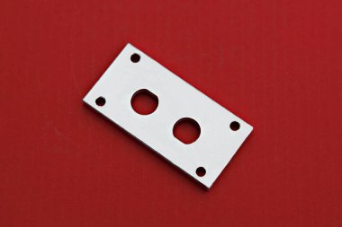 Kırmızı bir yüzeyde metal bir plaka.