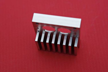 Kırmızı bir yüzey üzerinde küçük gümüş ve kırmızı bir elektronik cihaz.