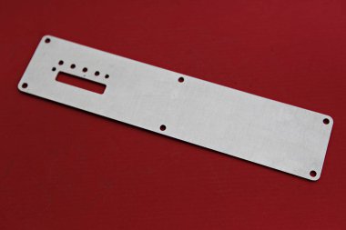 Kırmızı yüzeyinde delikleri olan metal bir plaka.
