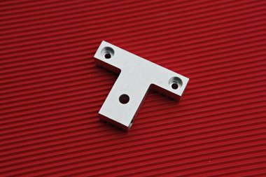 Kırmızı bir yüzeyde metal bir t