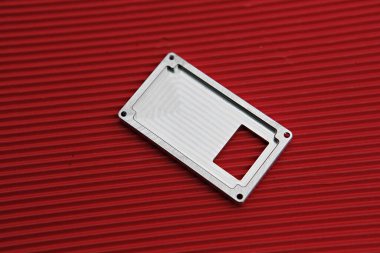 Kırmızı bir yüzeyde metal bir plaka.