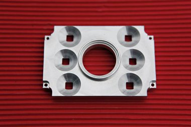 Kırmızı yüzeyinde delikleri olan metal bir nesne.