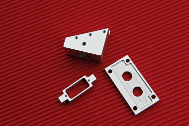 Kırmızı bir yüzeyde bir çift metal parçası.