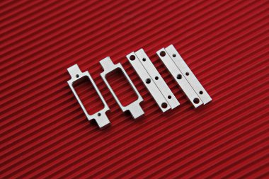 Kırmızı bir yüzeyde bir çift metal parçası.