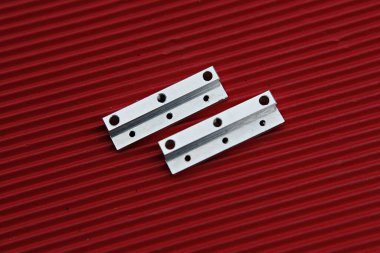 Kırmızı bir yüzeyde iki metal parçası