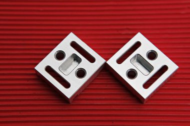 Kırmızı bir yüzeyde iki metal parçası