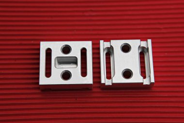 Kırmızı bir yüzeyde iki metal parçası