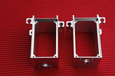 Kırmızı bir yüzeyde iki metal kutu.