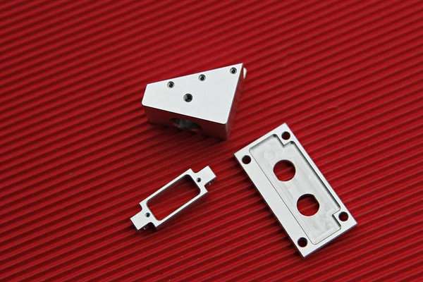 Kırmızı bir yüzeyde bir çift metal parçası.