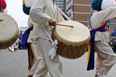 Bir grup beyaz elbiseli adam davul çalıyor.