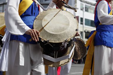 Geleneksel giyimli bir grup erkek davul çalıyor.