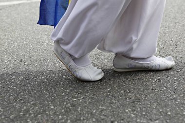 Mavi çantalı ve beyaz ayakkabılı bir adam.