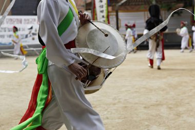 Beyaz elbiseli bir adam davul taşıyor.