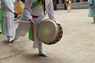 Elinde davul tutan beyaz elbiseli bir adam.