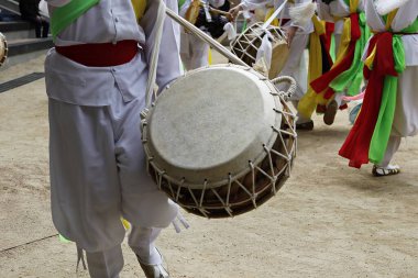 Bir grup beyaz elbiseli insan davul çalıyor.