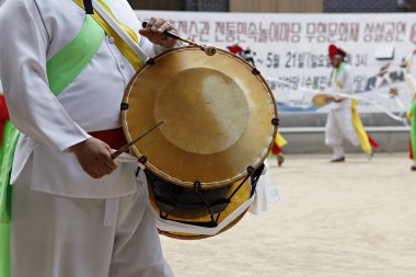 Elinde davul tutan beyaz takım elbiseli bir adam.