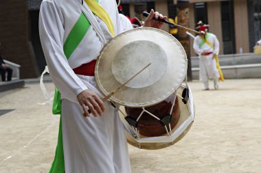 Beyaz elbiseli bir adam davul çalıyor.