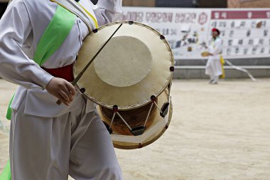 Elinde davul tutan beyaz elbiseli bir adam.